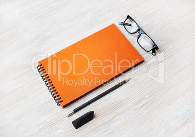 Orange notepad, glasses, pencil, eraser
