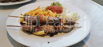 Pork skewers on wooden skewers with vegetables and fried potatoes