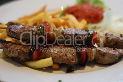 Pork skewers on wooden skewers with vegetables and fried potatoes