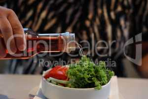 Pour wine vinegar on fresh lettuce with tomatoes, cucumber and herbs