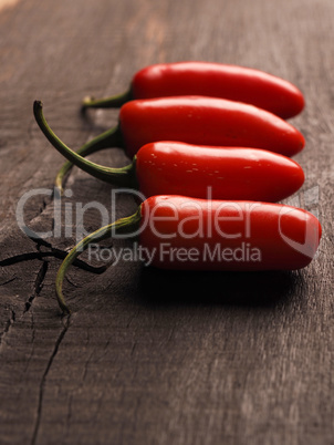 Four freshly harvested homegrown hot peppers on a rustic kitchen