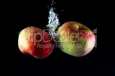 Two apples in water on a black background