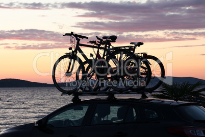 Bicycles by car on a sunset background