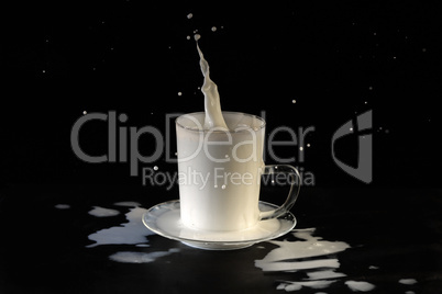 Milk splashes out of a glass goblet