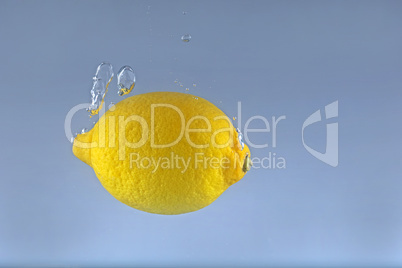 A whole lemon falls into the water with a splash