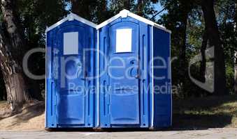 Two portable toilet cabins in park at dry sunny summer day