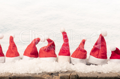 Hats of Santa in a row on a rustic wooden table, panoramic view