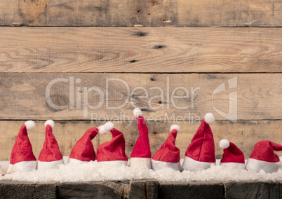 Hats of Santa in a row on a rustic wooden table, panoramic view