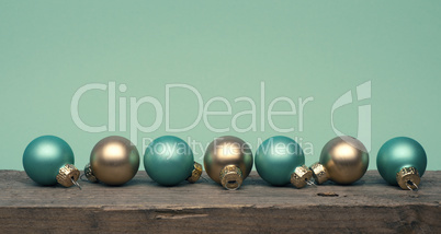 Golden and turquoise Christmas tree baubles on a wooden table