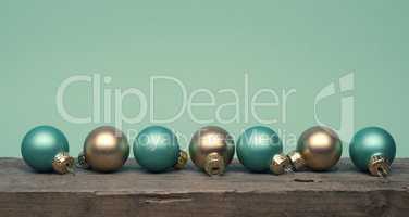 Golden and turquoise Christmas tree baubles on a wooden table