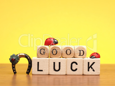Wooden blocks with good luck on yellow background