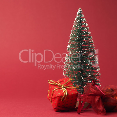 Red Christmas gift box with golden bow and decoration on a red p