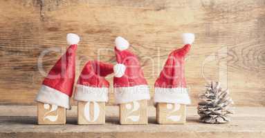 Four wooden blocks with hats of Santa and the Year number 2022