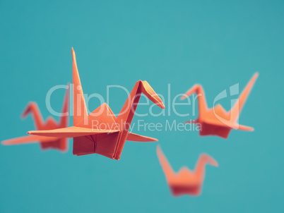 Four origami cranes on a blue background
