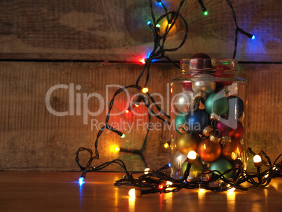 A candy jar filled with Christmas balls and decorated with color