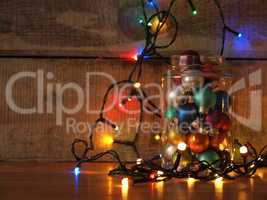 A candy jar filled with Christmas balls and decorated with color