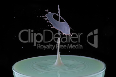 A drop of milk falls into a cup
