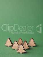 Small wooden Christmas tree shapes on a green background