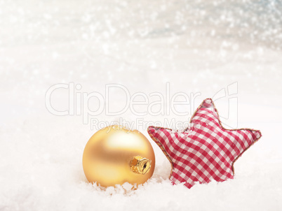 Checkered star shape with golden Christmas bauble in snow