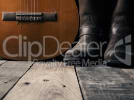 Old cowboy boots  with an acoustic guitar on barn wood