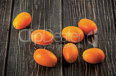 Several ripe kumquats on a wooden table