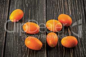 Several ripe kumquats on a wooden table