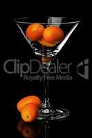 Ripe kumquat in martini glass with reflection