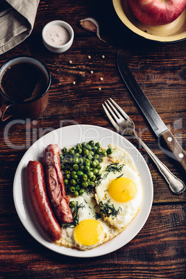 Breakfast with fried eggs, sausages and green peas