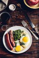 Breakfast with fried eggs, sausages and green peas