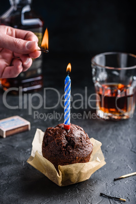 Hand lighting candle on birthday muffin