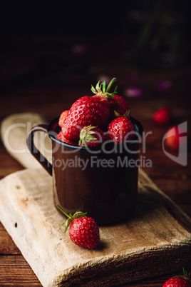 Mug full of fresh strawberries on rustic table