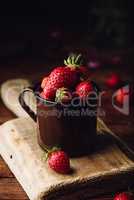 Mug full of fresh strawberries on rustic table