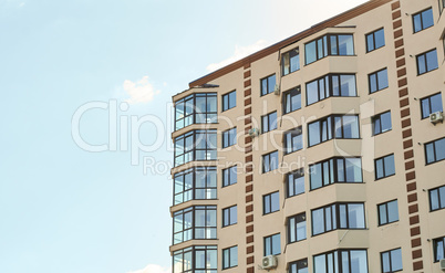 Block of flats. New residential apartment condominium type. City real estate. Simple condo architecture. View of modern sand stucco facade with big bay window balcony and casement solid glass windows