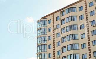 Block of flats. New residential apartment condominium type. City real estate. Simple condo architecture. View of modern sand stucco facade with big bay window balcony and casement solid glass windows