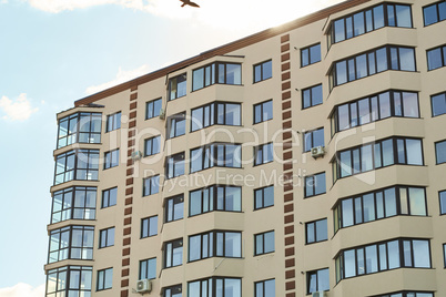 City real estate. Simple condo architecture. New residential apartment condominium type. Block of flats. View of modern sand stucco facade with big bay window balcony and casement solid glass windows