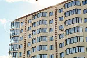 City real estate. Simple condo architecture. New residential apartment condominium type. Block of flats. View of modern sand stucco facade with big bay window balcony and casement solid glass windows