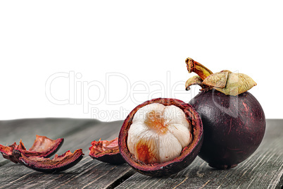 Whole and opened mangosteen with shells on table