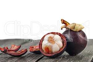 Whole and opened mangosteen with shells on table