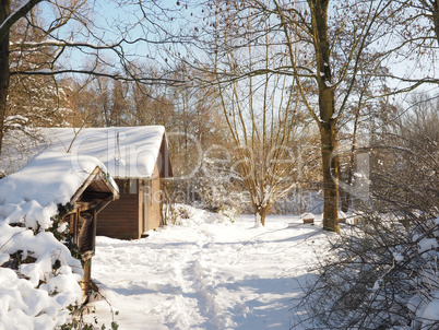 Wooden hut in a piece of forest, covered with snow after a heavy