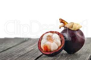 Whole and opened mangosteen on table isolated on white
