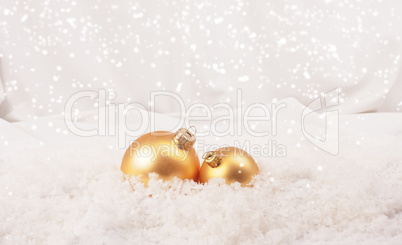 Two golden Christmas baubles in snow
