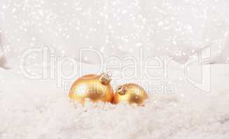 Two golden Christmas baubles in snow