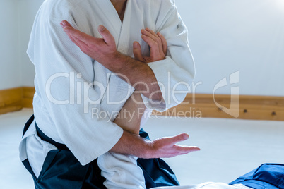 Man practicing aikido in a dojo background.