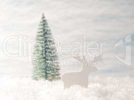 Small reindeer wooden figure in the snow with Christmas tree