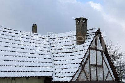 The roof of an old house is covered with snow in winter