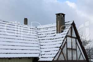 The roof of an old house is covered with snow in winter