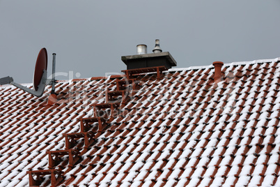 The tiled roof of the house is covered with snow in winter