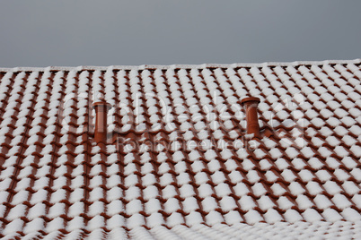 The tiled roof of the house is covered with snow in winter