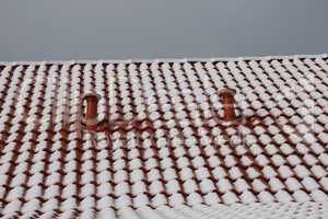 The tiled roof of the house is covered with snow in winter