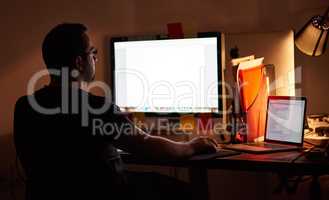 Working late into the night. Cropped shot of a young man working late in his office.